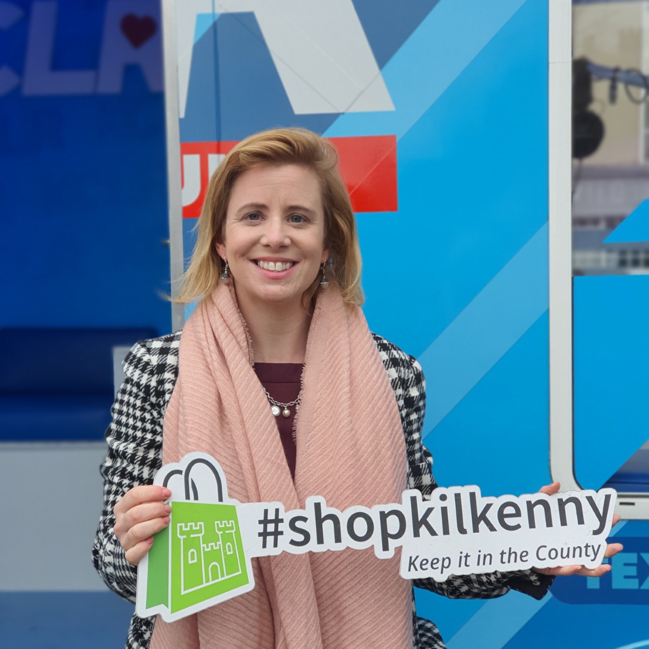 KCLR Live presenter Eimear Ní Bhraonáin holds a Shop Kilkenny sign on The Parade, Kilkenny